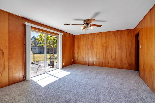 carpeted empty room featuring ceiling fan and wood walls