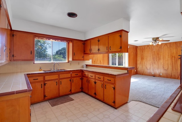 kitchen with decorative backsplash, tile countertops, kitchen peninsula, sink, and ceiling fan