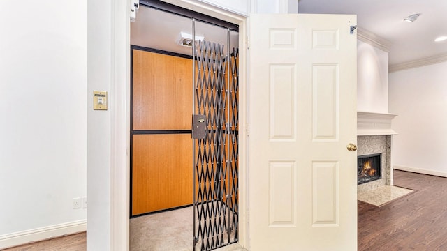 room details featuring ornamental molding, a high end fireplace, hardwood / wood-style flooring, and elevator