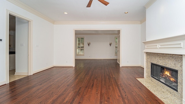 unfurnished living room with crown molding, a high end fireplace, dark wood-type flooring, and ceiling fan