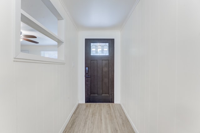 doorway to outside featuring wood walls, ornamental molding, and light hardwood / wood-style flooring