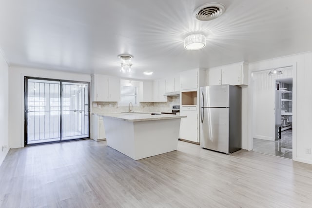 kitchen featuring tasteful backsplash, white cabinetry, stainless steel appliances, light hardwood / wood-style floors, and a center island