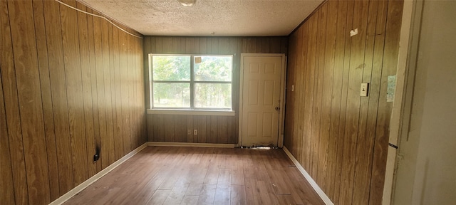 spare room featuring hardwood / wood-style floors, a textured ceiling, and wooden walls