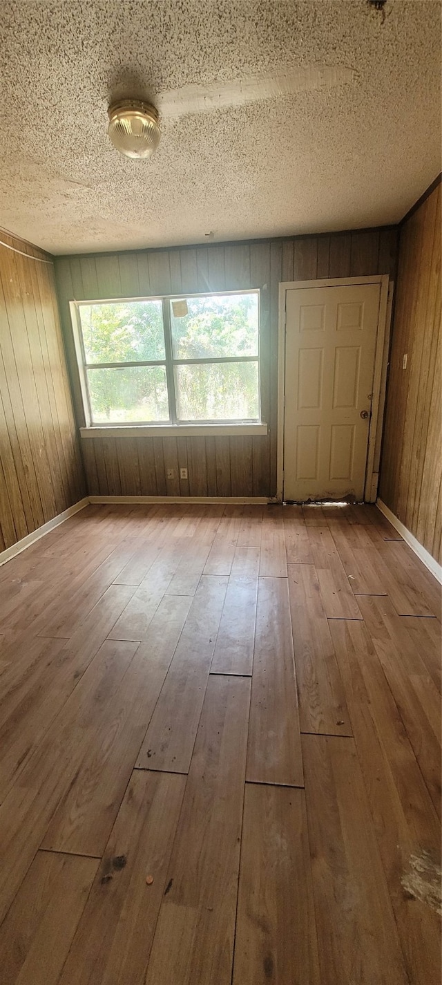 spare room featuring hardwood / wood-style floors, a textured ceiling, and wooden walls