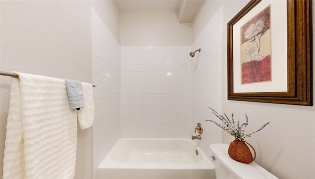 bathroom with toilet and tiled shower / bath