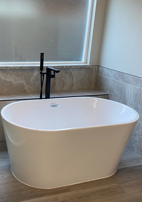 bathroom with tile walls, hardwood / wood-style flooring, and a tub