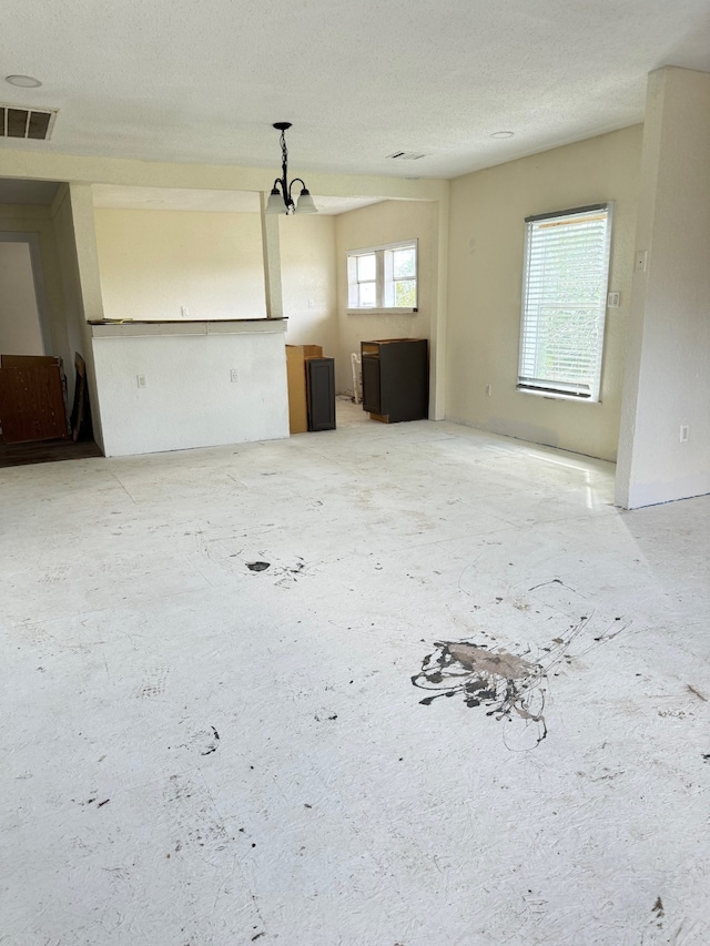 unfurnished living room with a textured ceiling and plenty of natural light