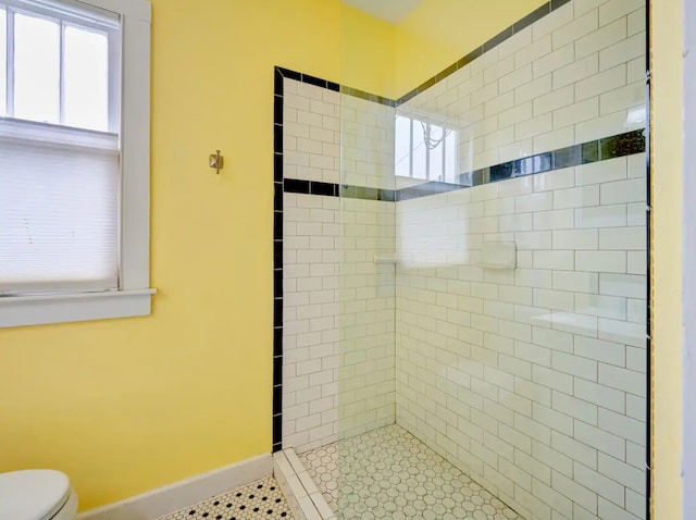 bathroom with toilet, tile patterned floors, and tiled shower