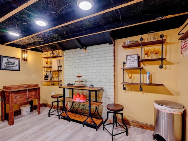 basement with brick wall and wood-type flooring