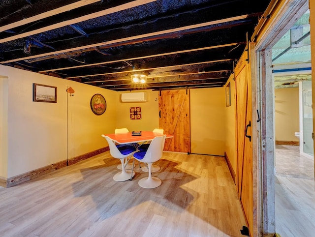 basement with hardwood / wood-style floors, a barn door, and a wall unit AC