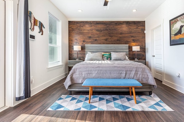 bedroom featuring wooden walls, dark hardwood / wood-style floors, and ceiling fan