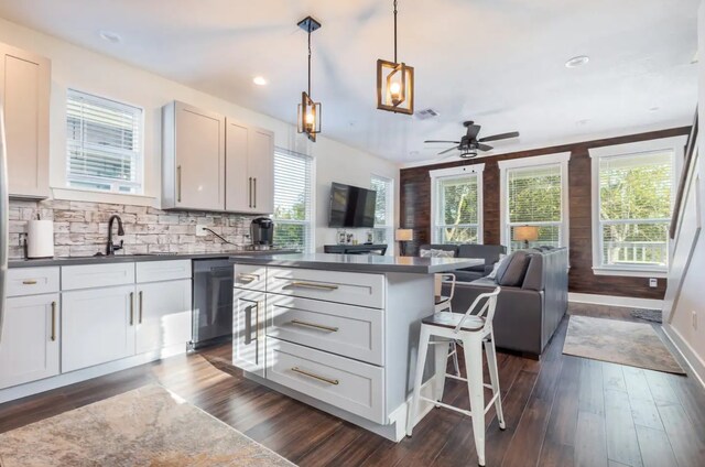 kitchen with a center island, pendant lighting, stainless steel dishwasher, white cabinets, and dark wood-type flooring