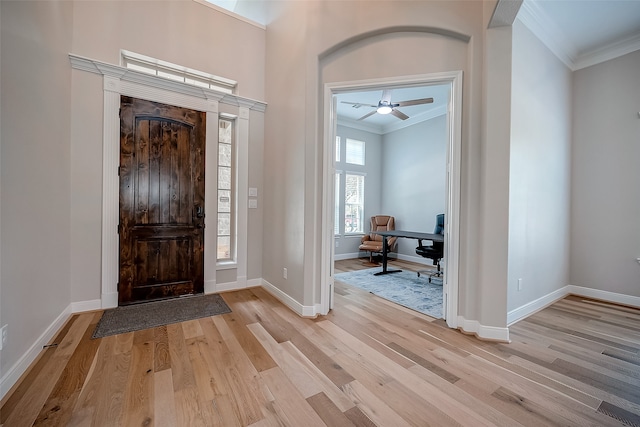 entryway with crown molding, light wood-type flooring, and ceiling fan