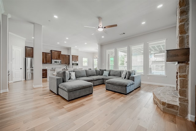 living room featuring crown molding, light hardwood / wood-style flooring, and a healthy amount of sunlight