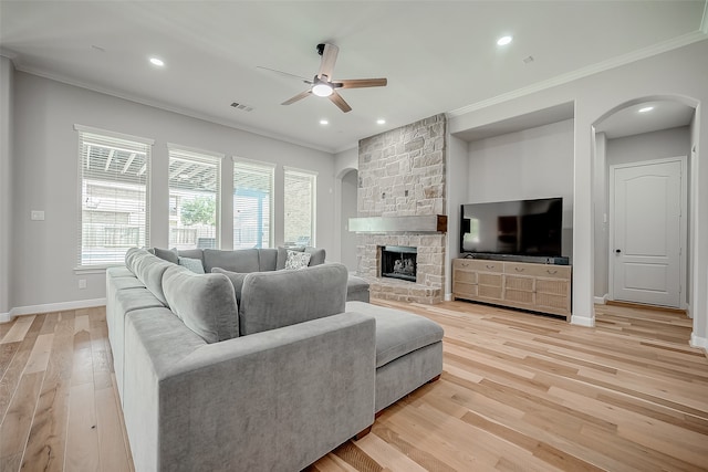 living room with crown molding, a fireplace, light wood-type flooring, and ceiling fan