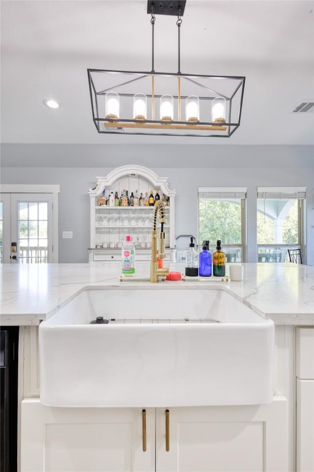 interior details with visible vents, recessed lighting, white cabinets, light stone counters, and a sink