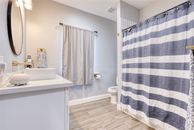 bathroom featuring vanity, toilet, wood-type flooring, and walk in shower