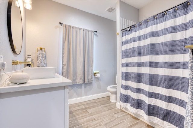 full bathroom featuring vanity, toilet, baseboards, wood finished floors, and visible vents