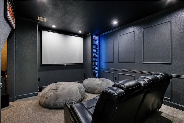 home theater room with ornamental molding, a textured ceiling, and carpet floors