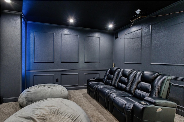 home theater room with a decorative wall, ornamental molding, carpet flooring, and a textured wall