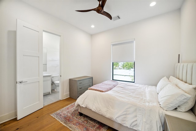 bedroom featuring light hardwood / wood-style floors, ensuite bathroom, and ceiling fan