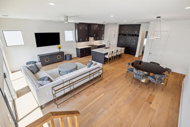 living room featuring sink, light wood-type flooring, and ceiling fan