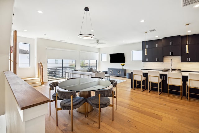 dining space with light hardwood / wood-style flooring, sink, and ceiling fan