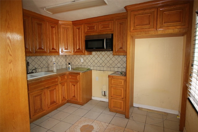 kitchen featuring decorative backsplash, light tile patterned flooring, and sink