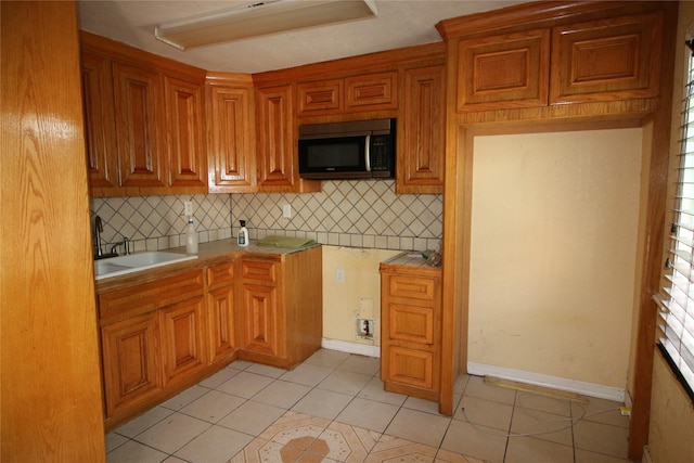 kitchen featuring decorative backsplash, brown cabinetry, and stainless steel microwave