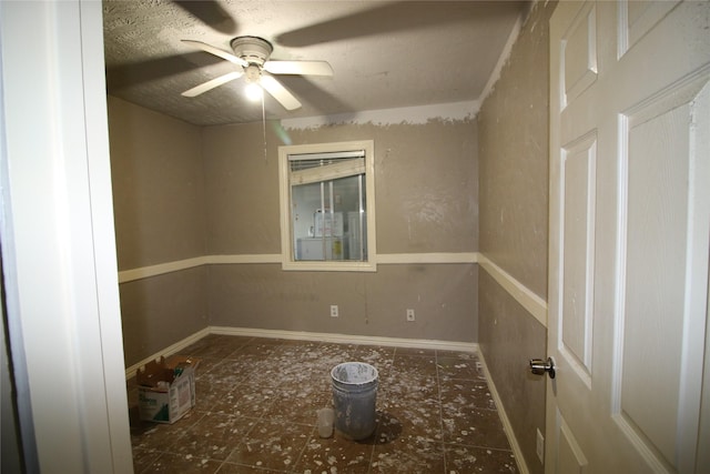 tiled empty room with a ceiling fan and baseboards