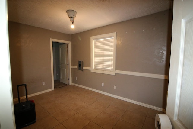 tiled spare room featuring baseboards, a textured ceiling, and electric panel