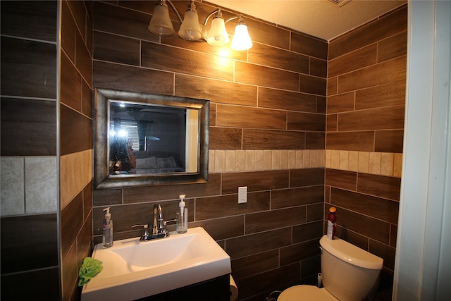 bathroom with vanity, toilet, and tile walls