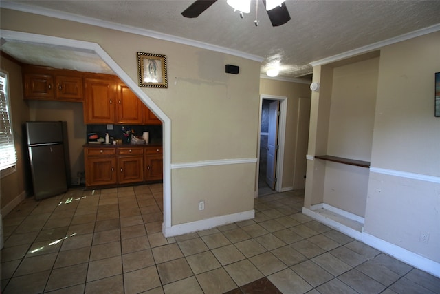 kitchen featuring tile patterned flooring, stainless steel fridge, crown molding, a textured ceiling, and ceiling fan