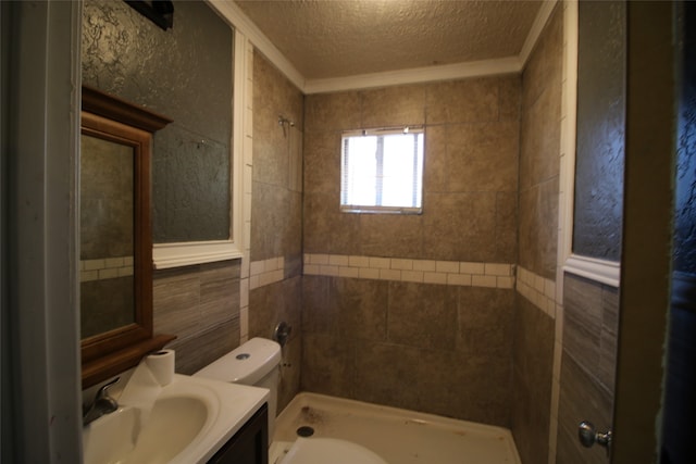 bathroom featuring a textured ceiling, toilet, tiled shower, vanity, and crown molding