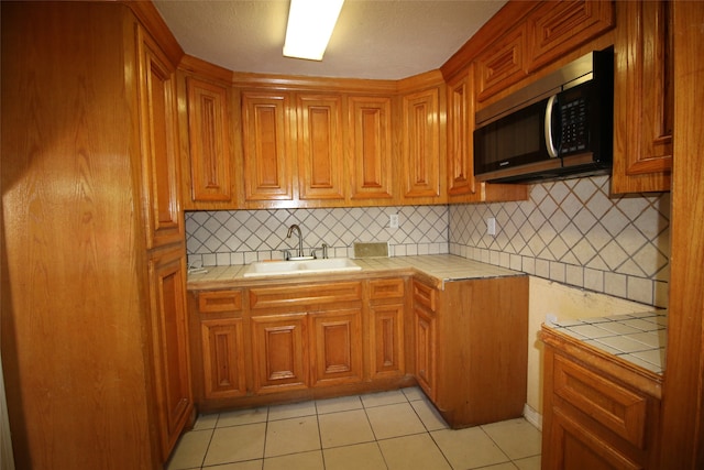 kitchen featuring backsplash, light tile patterned flooring, sink, and tile counters