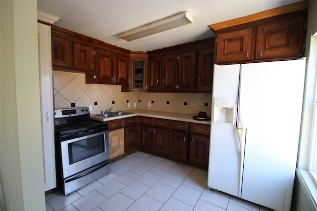 kitchen featuring electric stove, white fridge with ice dispenser, sink, and backsplash