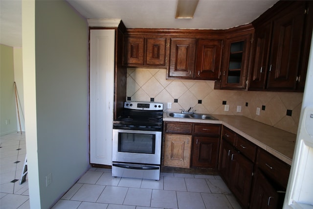 kitchen featuring sink, electric stove, dark brown cabinetry, decorative backsplash, and light tile patterned floors