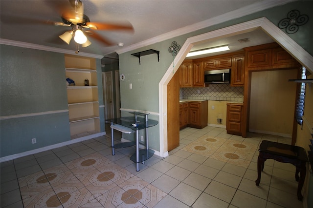 kitchen featuring brown cabinetry, ornamental molding, stainless steel microwave, and ceiling fan