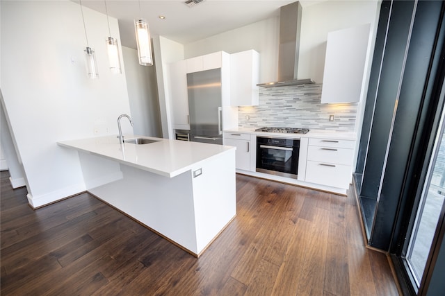 kitchen featuring white cabinetry, sink, wall chimney exhaust hood, pendant lighting, and appliances with stainless steel finishes