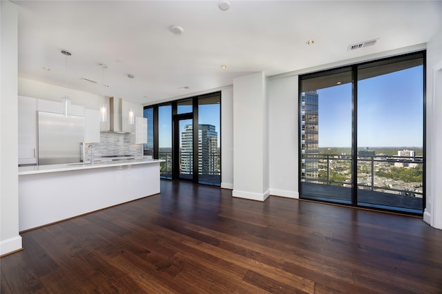 unfurnished living room with floor to ceiling windows, dark hardwood / wood-style floors, and a wealth of natural light