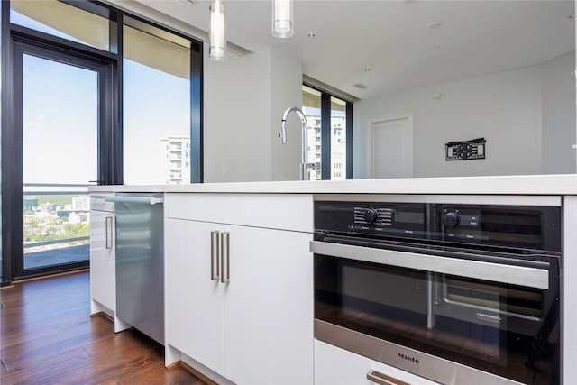 kitchen featuring white cabinets, decorative light fixtures, dark hardwood / wood-style floors, and a wall of windows