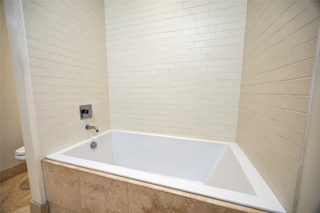 bathroom with a relaxing tiled tub and toilet