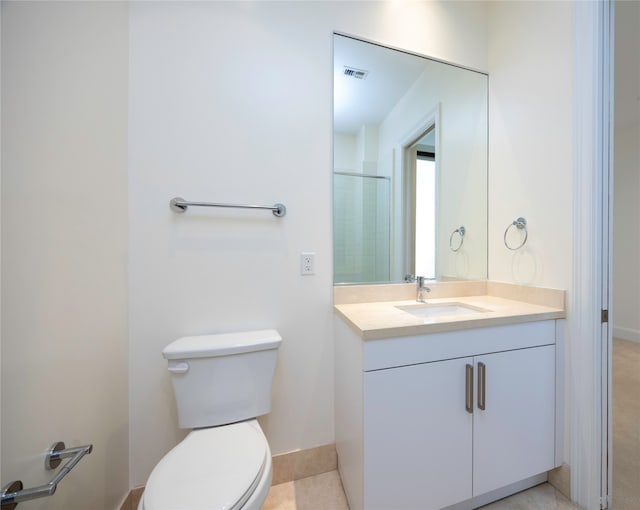 bathroom featuring tile patterned flooring, vanity, toilet, and a shower with door