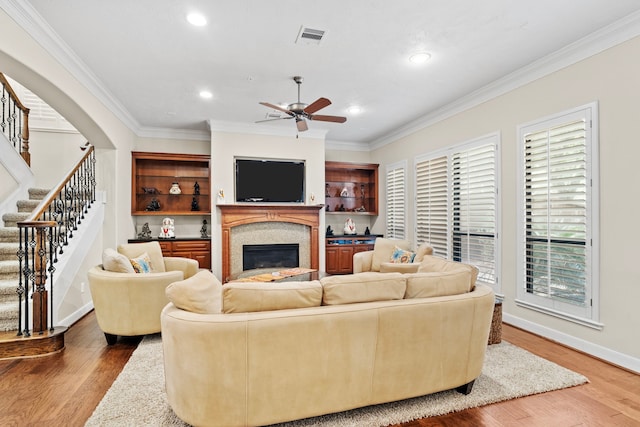 living room featuring ornamental molding, wood-type flooring, and ceiling fan