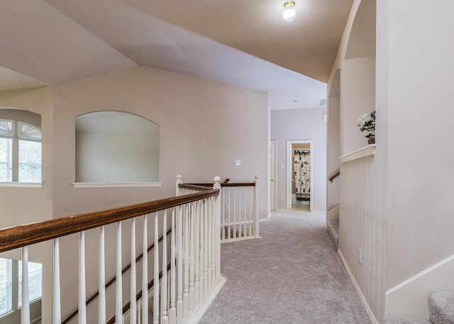 hallway featuring light colored carpet, a healthy amount of sunlight, and vaulted ceiling