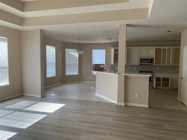 kitchen featuring tasteful backsplash, a wealth of natural light, cream cabinets, and stainless steel appliances