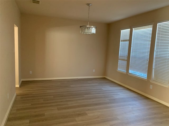 spare room featuring a chandelier and wood-type flooring