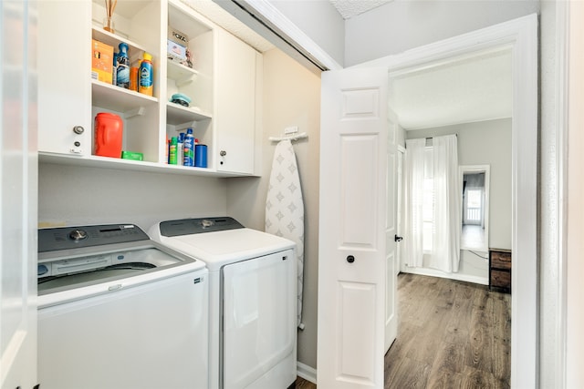 laundry room featuring cabinets, hardwood / wood-style floors, and washing machine and dryer