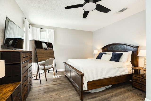 bedroom featuring ceiling fan, a textured ceiling, and dark hardwood / wood-style flooring