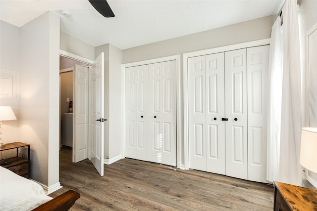 bedroom featuring ceiling fan, hardwood / wood-style flooring, a textured ceiling, and two closets